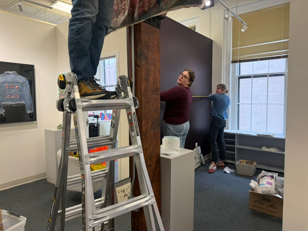 Gallery staff on a ladder installing work during call setup
