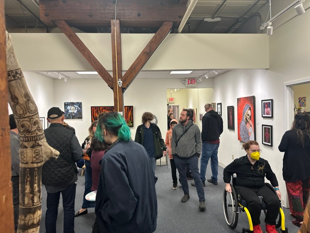 Gallery crowd at an opening, including visitors of varied ages and abilities