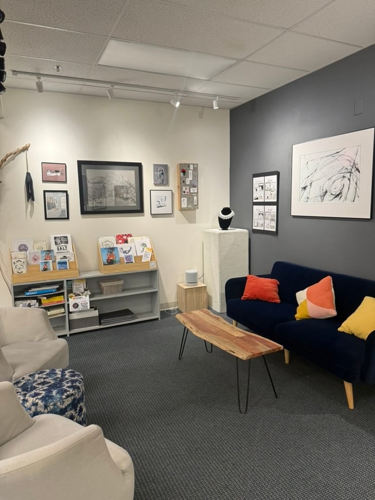 A quiet gallery room with a sofa and framed work on the walls.