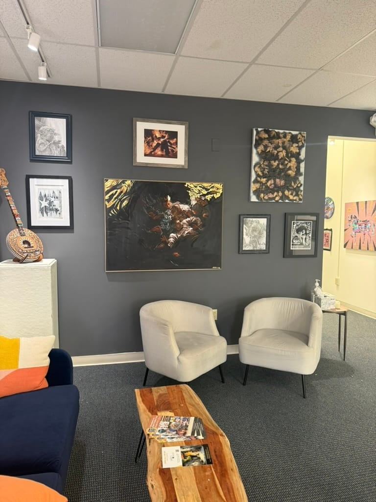 A quiet gallery sitting room with framed work above a calm review space