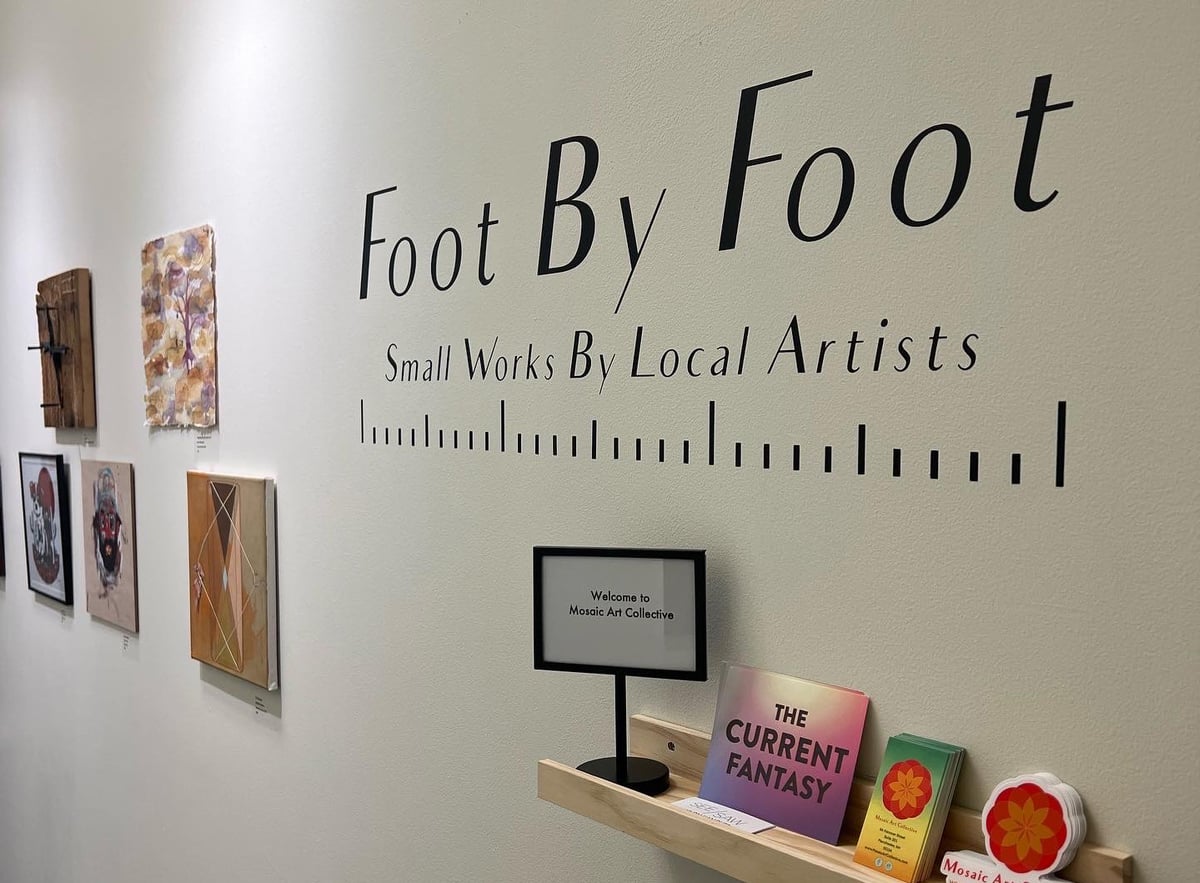 Gallery wall lettering reads 'Foot By Foot — Small Works By Local Artists' next to a row of small framed pieces