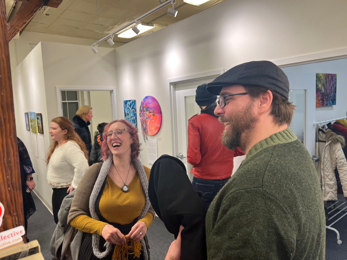 Two gallery patrons laughing together at an opening reception